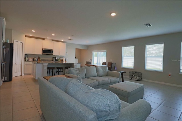 living area with light tile patterned flooring, visible vents, recessed lighting, and baseboards