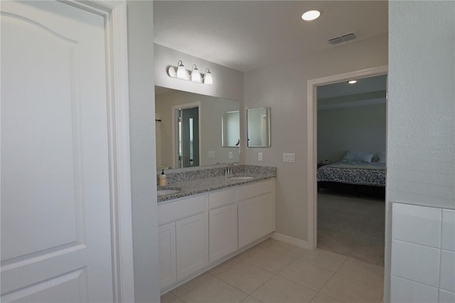 bathroom with visible vents, double vanity, a sink, tile patterned floors, and connected bathroom