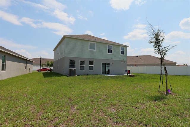 rear view of property featuring a yard, central AC unit, and fence