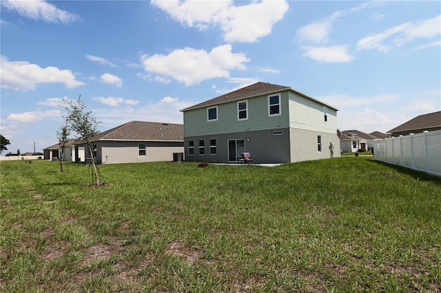 back of property featuring a yard, central AC unit, stucco siding, and fence