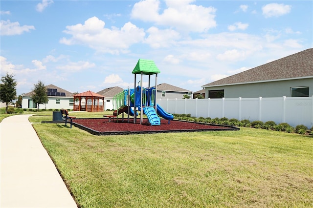 communal playground featuring a yard and fence