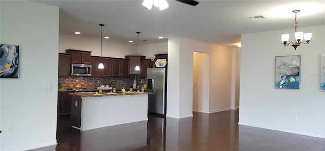 kitchen with appliances with stainless steel finishes, dark wood-type flooring, ceiling fan with notable chandelier, pendant lighting, and a center island