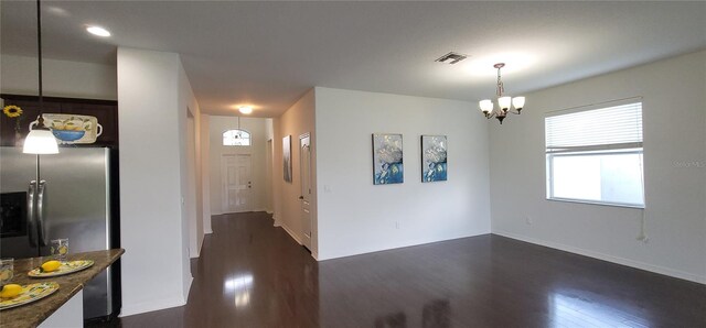 interior space with stainless steel refrigerator with ice dispenser, a chandelier, dark hardwood / wood-style floors, and decorative light fixtures