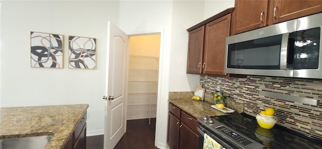 kitchen with tasteful backsplash, dark wood-type flooring, stainless steel appliances, and light stone counters