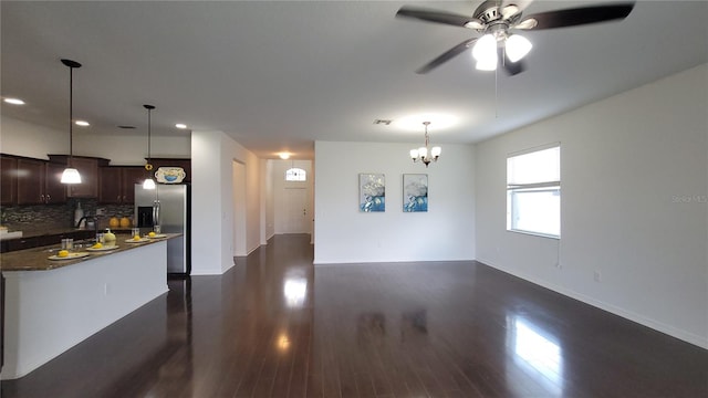 kitchen featuring stainless steel refrigerator with ice dispenser, ceiling fan with notable chandelier, backsplash, and dark wood-type flooring