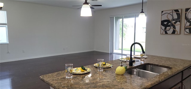 kitchen featuring dark hardwood / wood-style flooring, stone countertops, ceiling fan, decorative light fixtures, and sink