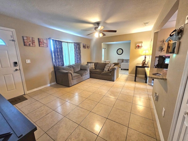 living room with ceiling fan, light tile patterned flooring, and a textured ceiling