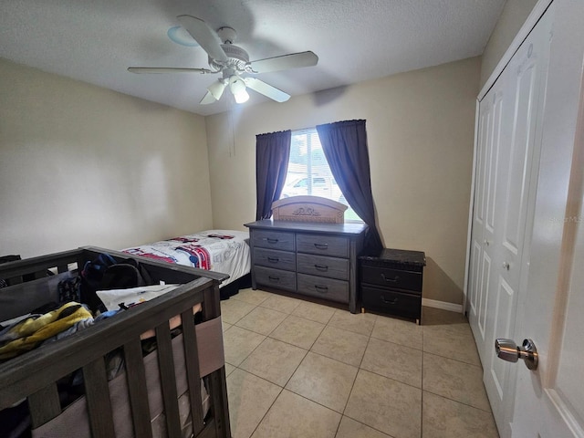 tiled bedroom with ceiling fan, a textured ceiling, and a closet