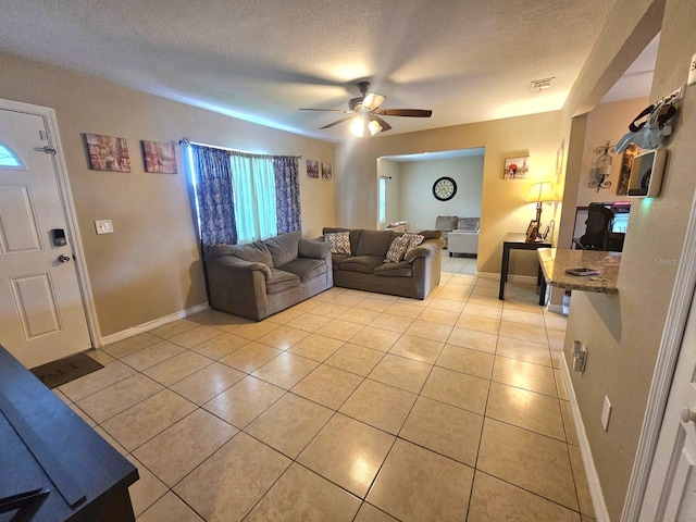 living room with ceiling fan, light tile patterned floors, and a textured ceiling