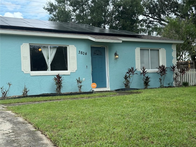 view of front facade featuring a front lawn and solar panels