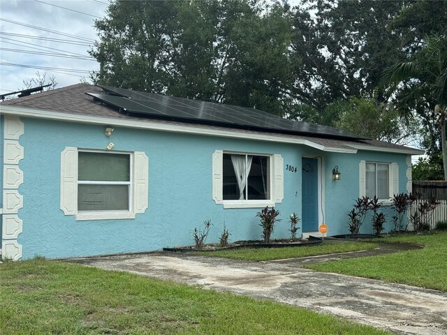 bungalow-style house featuring solar panels and a front yard