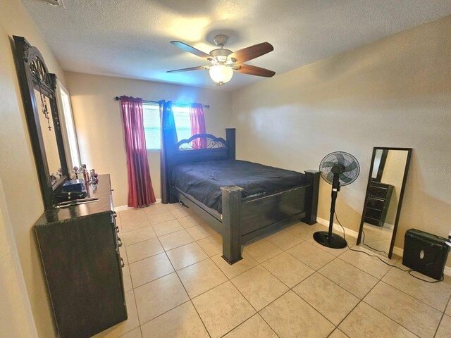 bedroom featuring ceiling fan, light tile patterned flooring, and a textured ceiling