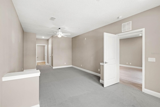 empty room with a textured ceiling, carpet floors, and ceiling fan