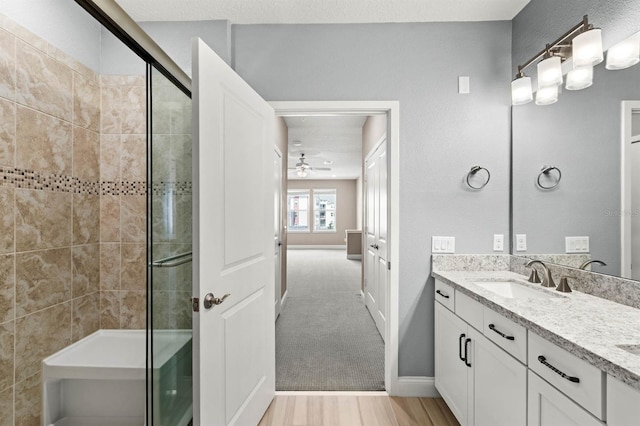 bathroom with ceiling fan, a textured ceiling, vanity, and a shower with shower door