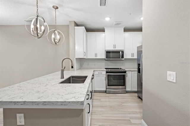 kitchen featuring appliances with stainless steel finishes, white cabinetry, a sink, and visible vents