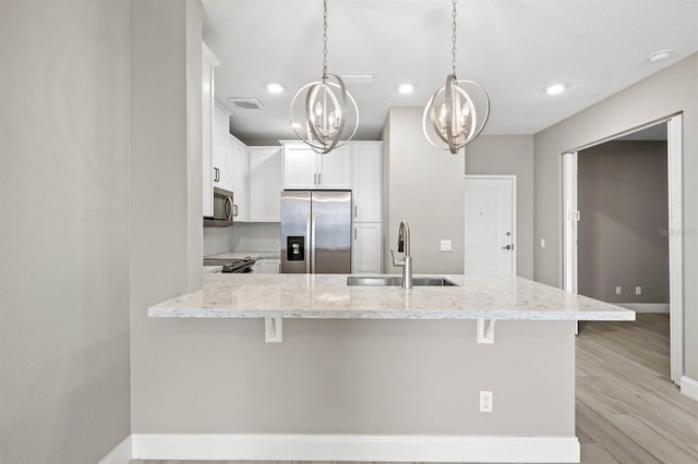 kitchen with decorative light fixtures, visible vents, appliances with stainless steel finishes, white cabinetry, and a sink