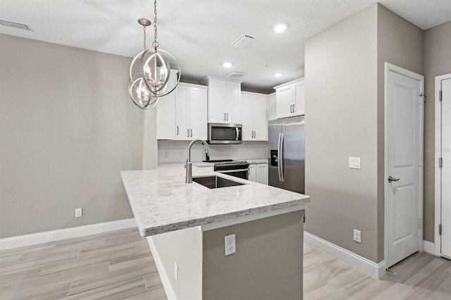 kitchen featuring a peninsula, visible vents, white cabinetry, hanging light fixtures, and appliances with stainless steel finishes