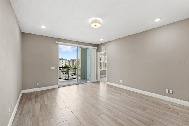 spare room featuring a textured ceiling, light wood-style flooring, recessed lighting, visible vents, and baseboards