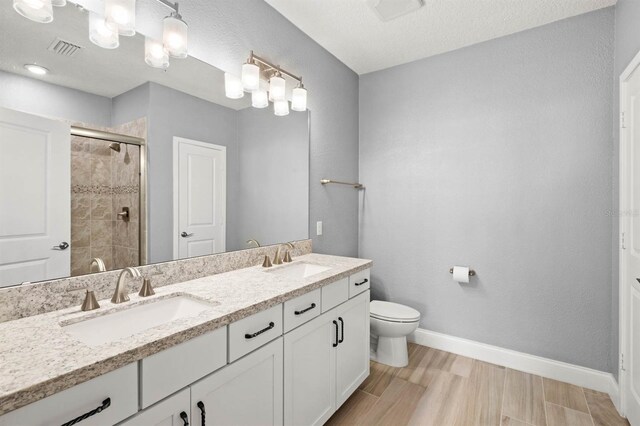 bathroom with a stall shower, a sink, visible vents, and baseboards