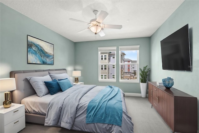 bedroom with light carpet, a textured ceiling, baseboards, and a ceiling fan