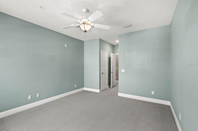 unfurnished room featuring carpet, visible vents, a ceiling fan, a textured ceiling, and baseboards