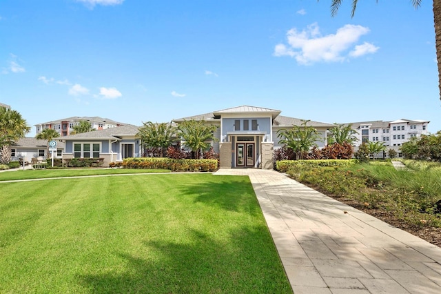 view of front of home with a standing seam roof, metal roof, and a front lawn