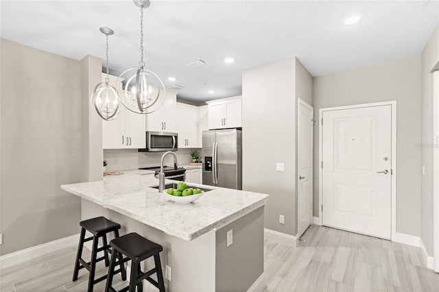 7573 Laureate Blvd Unit 1301, Orlando, FL 32827 - kitchen featuring stainless steel appliances, a chandelier, baseboards, a kitchen breakfast bar, and white cabinets