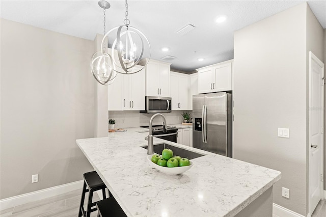 7573 Laureate Blvd Unit 1301, Orlando, FL 32827 - kitchen with stainless steel appliances, baseboards, a chandelier, a peninsula, and light stone countertops