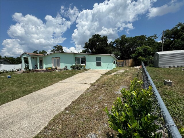 manufactured / mobile home with a front lawn, an outdoor structure, fence, and stucco siding