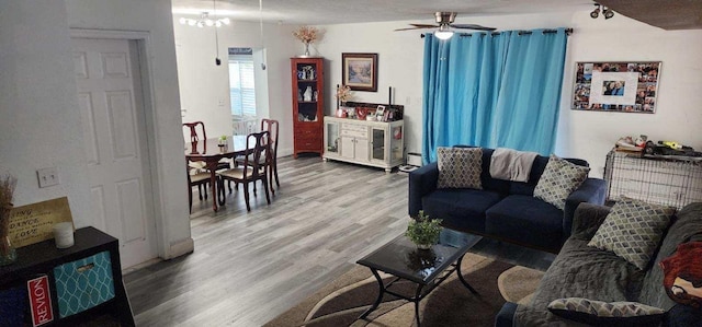 living room with ceiling fan with notable chandelier and wood finished floors