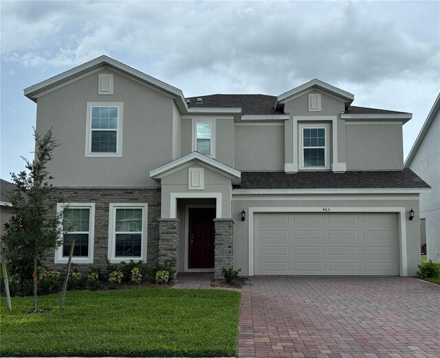 view of front of home featuring roof with shingles, a front lawn, decorative driveway, and stucco siding