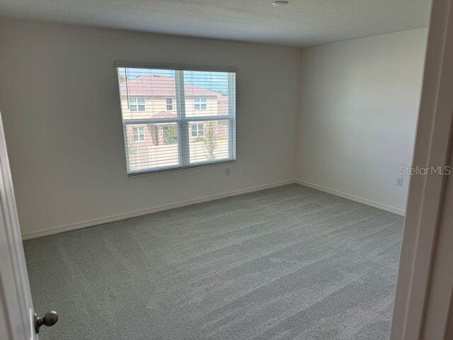 carpeted spare room featuring a textured ceiling