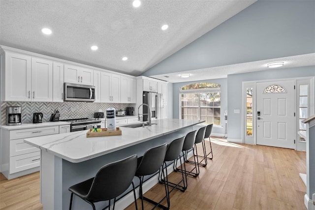 kitchen with white cabinets, an island with sink, stainless steel appliances, and sink