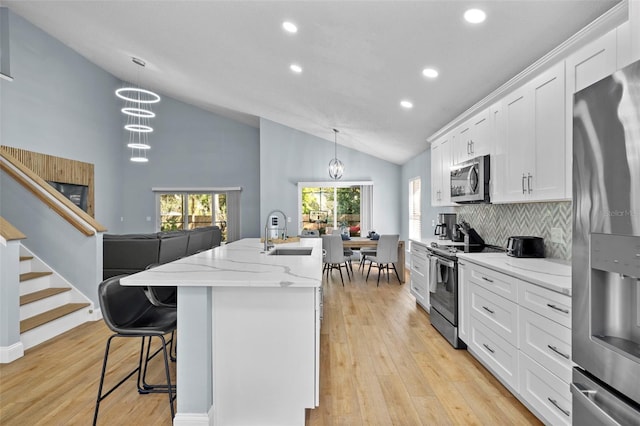 kitchen featuring white cabinets, a center island with sink, sink, appliances with stainless steel finishes, and light hardwood / wood-style floors