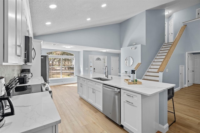 kitchen featuring white cabinetry, sink, a textured ceiling, a kitchen island with sink, and appliances with stainless steel finishes