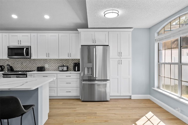 kitchen featuring white cabinets, appliances with stainless steel finishes, and light wood-type flooring