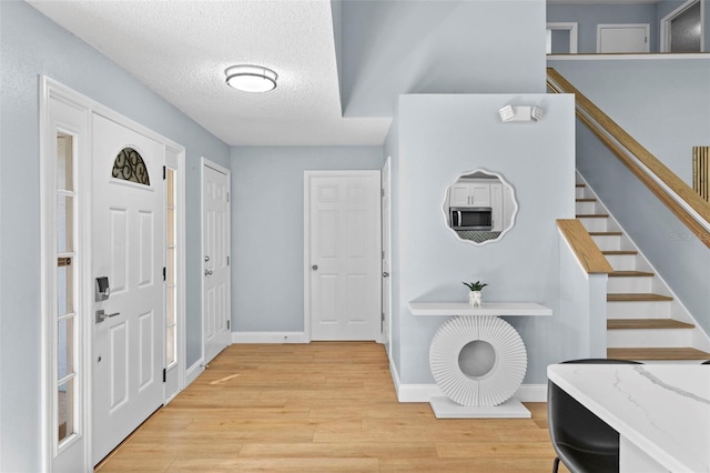 foyer entrance with light hardwood / wood-style floors and a textured ceiling