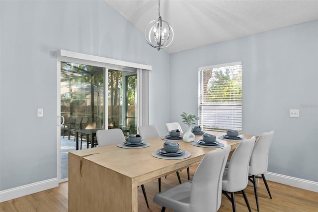 dining space with a chandelier, a textured ceiling, light wood-type flooring, and lofted ceiling