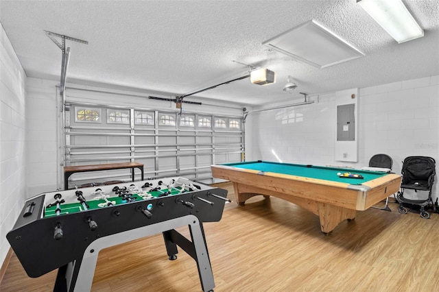 game room with electric panel, light wood-type flooring, a textured ceiling, and pool table