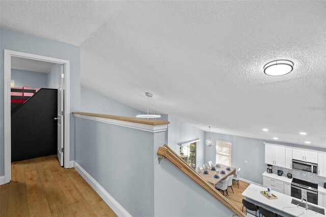 corridor featuring sink, a textured ceiling, and light hardwood / wood-style flooring