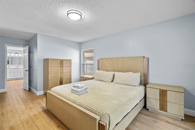 bedroom featuring ensuite bathroom, light hardwood / wood-style floors, and a textured ceiling