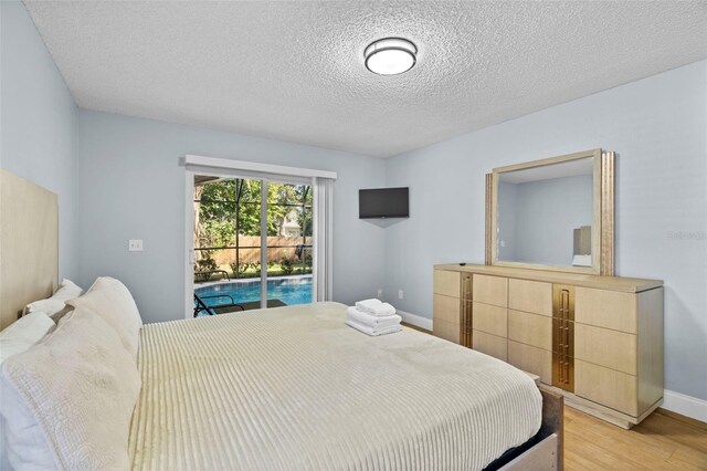 bedroom with access to outside, a textured ceiling, and light wood-type flooring