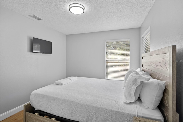 bedroom featuring hardwood / wood-style floors and a textured ceiling