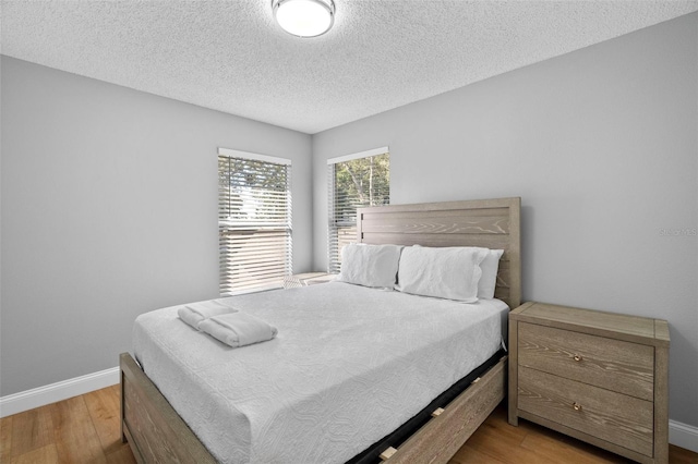 bedroom featuring light hardwood / wood-style floors and a textured ceiling