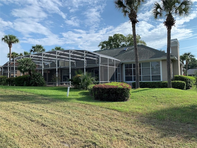 rear view of property featuring glass enclosure and a yard