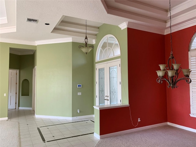 tiled foyer entrance with a textured ceiling, a notable chandelier, and a raised ceiling