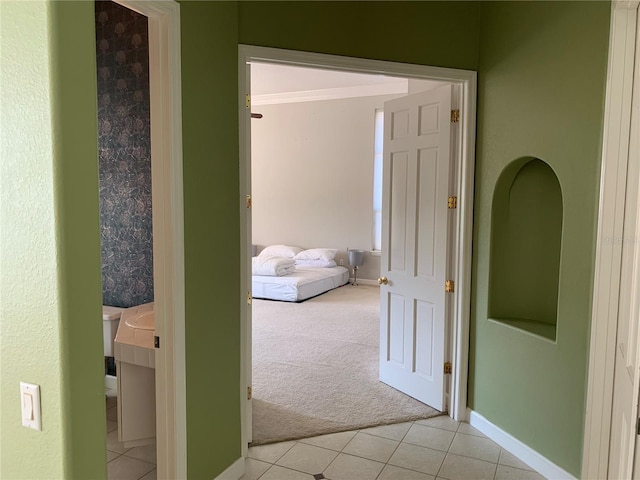 hallway with light colored carpet and crown molding