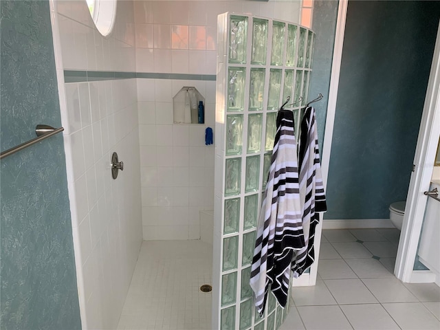 bathroom with tile patterned floors, a tile shower, and toilet