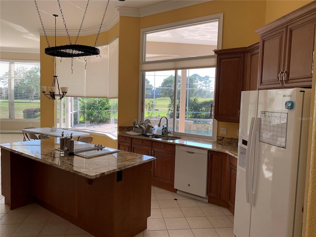 kitchen with a center island, sink, light tile patterned floors, a kitchen breakfast bar, and white appliances