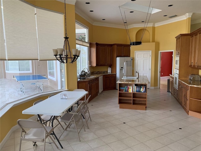 kitchen with light tile patterned flooring, a wealth of natural light, sink, and white appliances